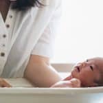mamá sujeta a bebé dentro de la bañera